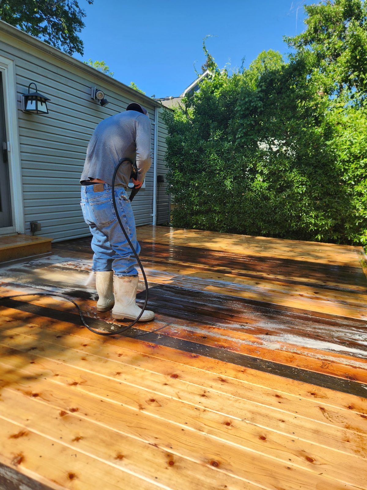 One of the crew staining a deck, half of it already finished in a warm golden tone