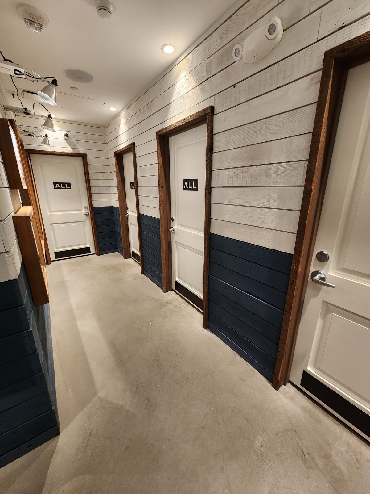Commercial corridor with shiplap walls, a dark base and timber doors