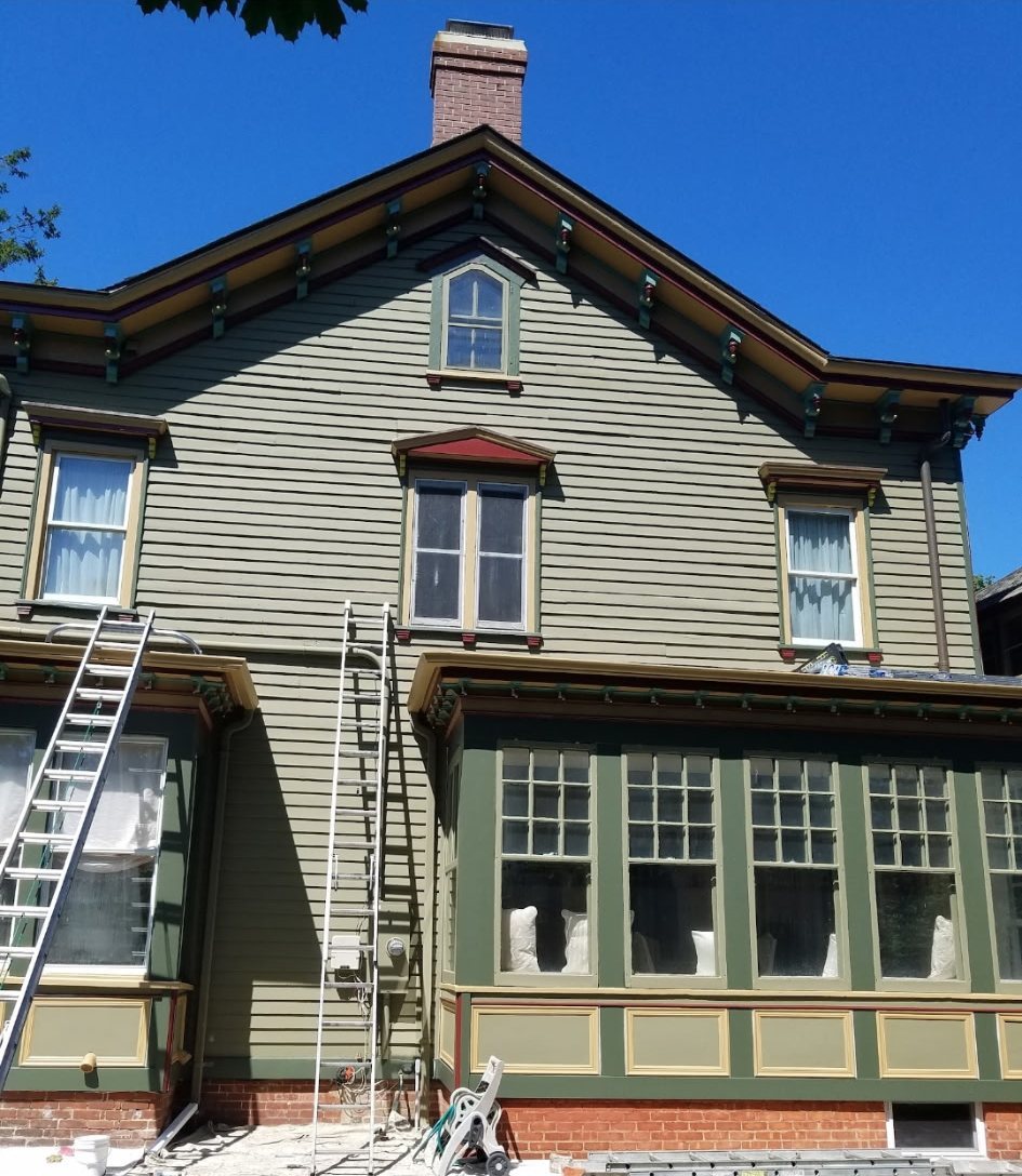 A Victorian house finished in sage green with cream, gold and deep green trim