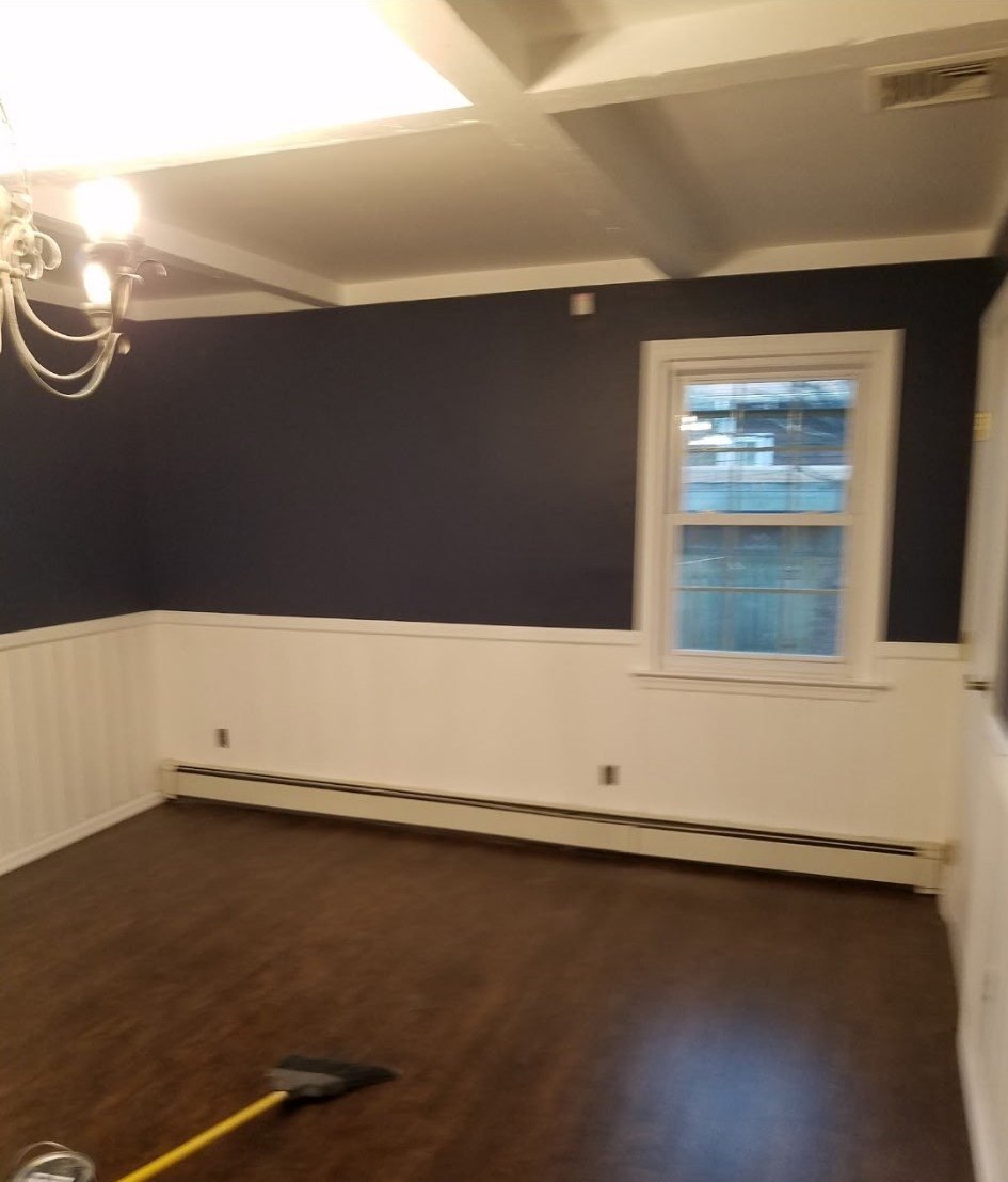 Room finished with a charcoal upper wall above white panelled wainscoting