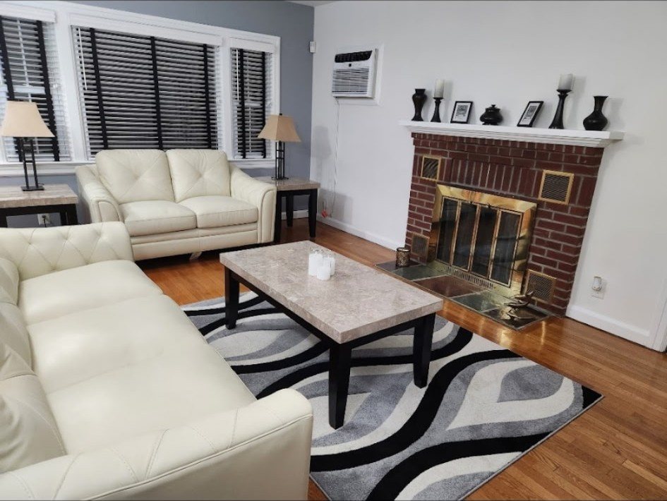 Living room with a brick fireplace, cream sofas and fresh white walls